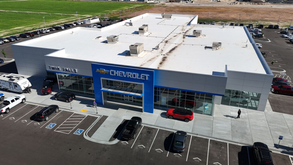 Aerial photo of the Twin Falls Chevrolet. There are multiple cars and RVs in the parking lot, and a single man walks towards the building door while on the phone.