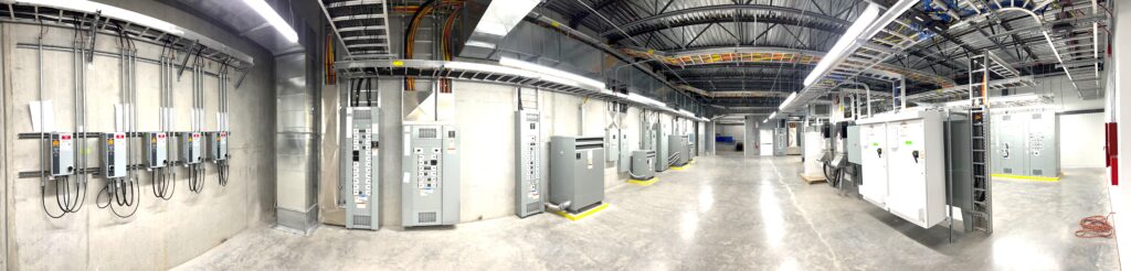 large panoramic image of an electrical room with exposed wiring and electrical panels throughout.