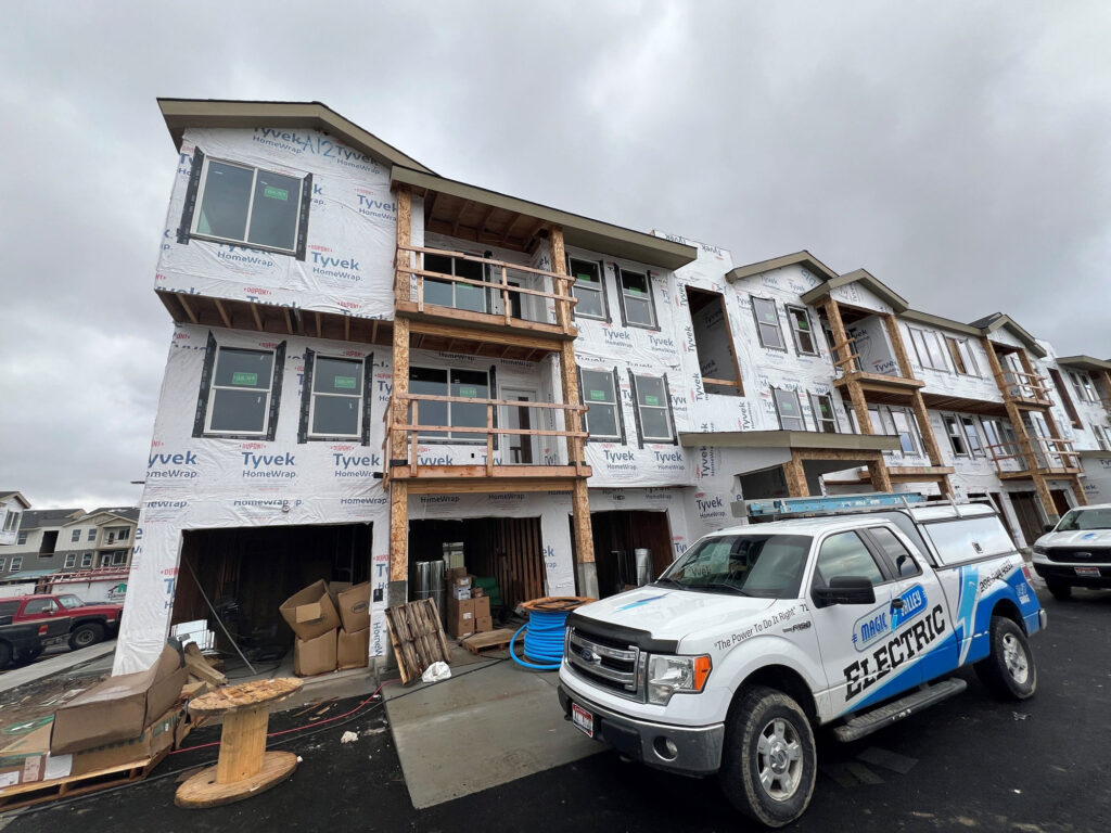 External photo of an apartment construction project. A truck with Magic Valley Electric branding can be seen parked in front of the construction project.