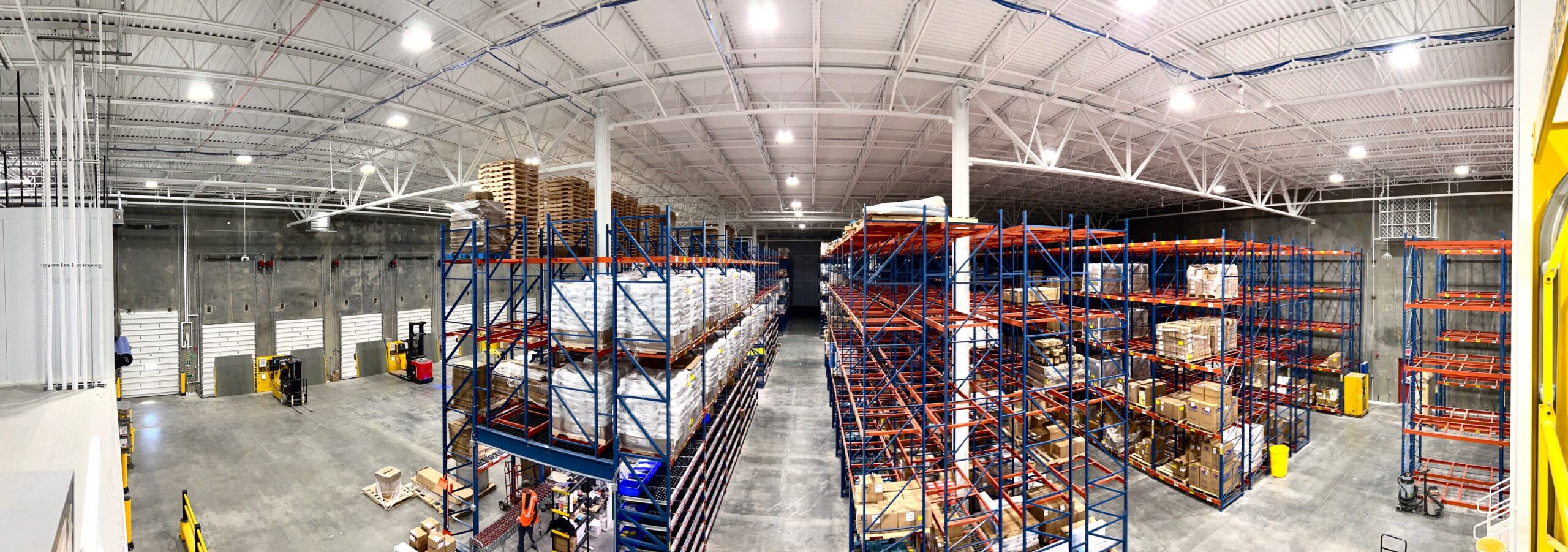 large panoramic image of a warehouse with shelving stacked with pallets of product.