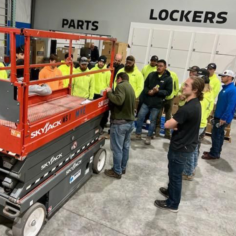 Image of the team during an OSHA practice meeting observing proper handling of a factory lift.