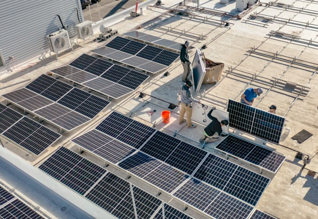 Image of employees installing solar panels on a commercial building